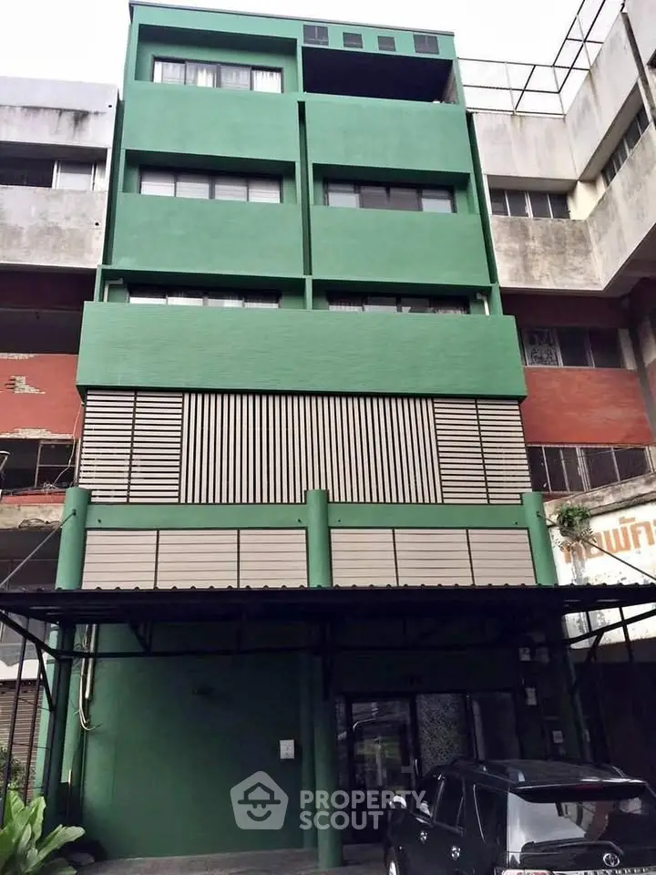 Modern green building exterior with parking area in urban setting
