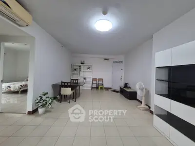 Spacious living room with modern furniture and tiled flooring in a well-lit apartment.