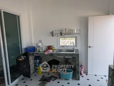 Compact kitchen with sink, storage, and sliding glass door in a minimalist design.