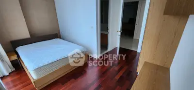 Spacious bedroom with wooden flooring and modern furnishings in a stylish apartment.