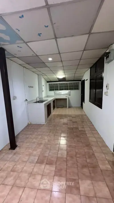 Spacious kitchen with tiled flooring and ample counter space in a cozy home.