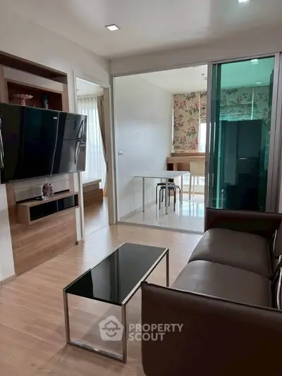 Modern living room with sleek furniture and open layout leading to dining area.