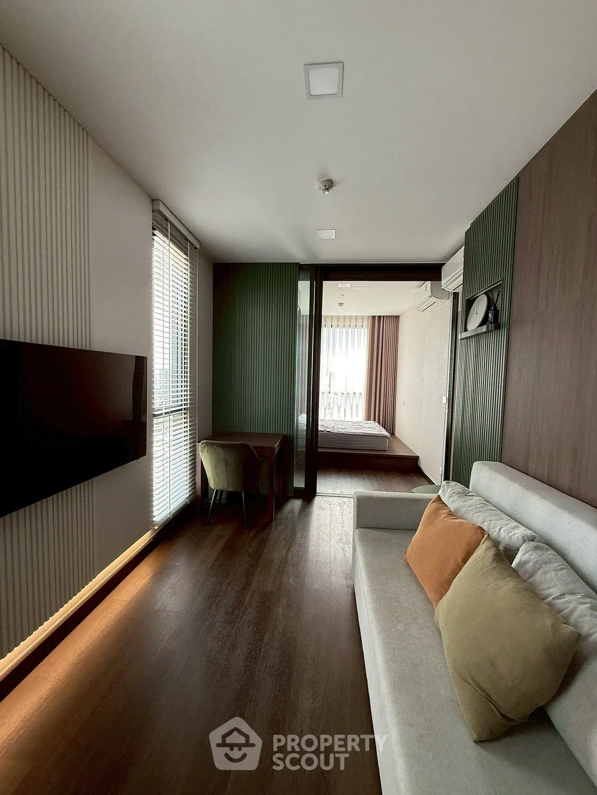 Modern living room with sleek design and natural light, featuring a cozy sofa and wall-mounted TV.