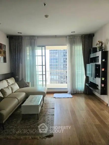 Modern living room with large windows and stylish furniture in a high-rise apartment.