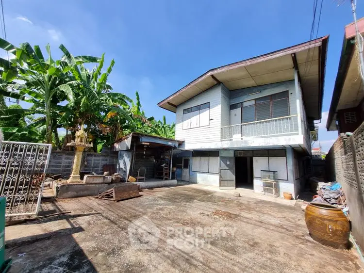 Charming two-story house with spacious outdoor area and lush banana trees.