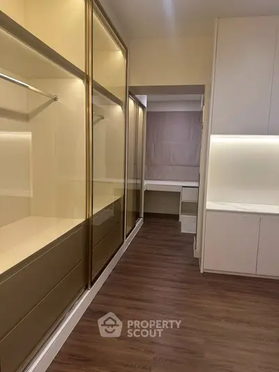 Spacious walk-in closet with elegant wooden flooring and ample storage space.