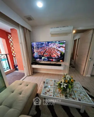 Modern living room with large TV and balcony access, featuring stylish decor and air conditioning.
