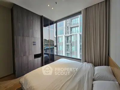 Modern bedroom with large window and city view in contemporary apartment