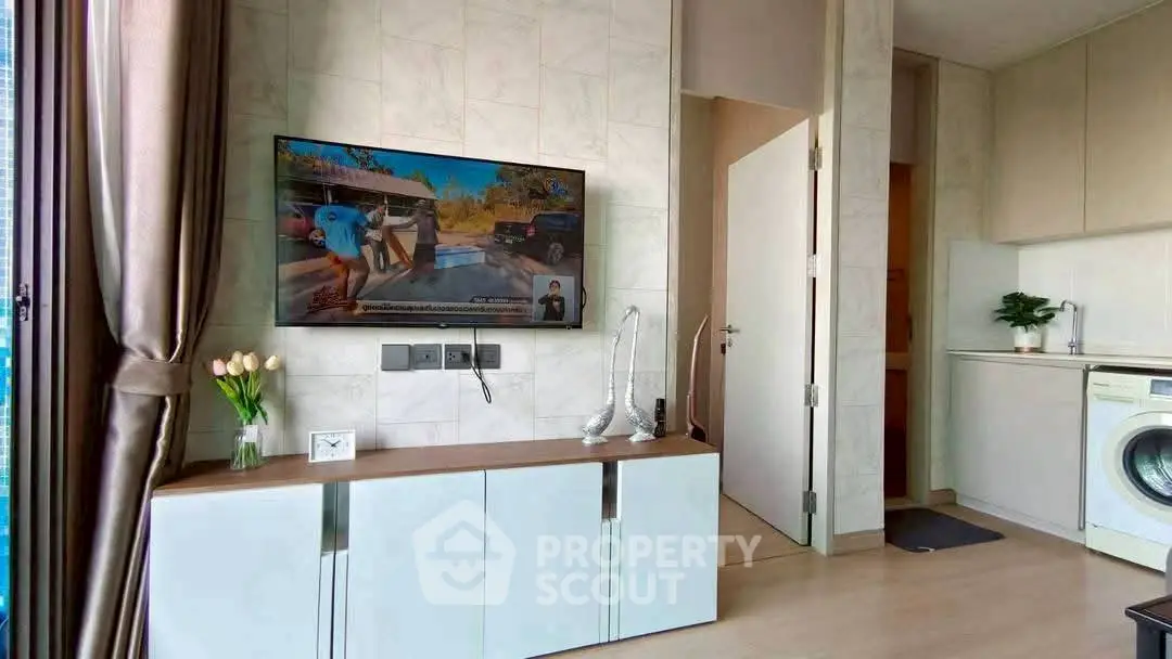 Modern living room with TV, stylish cabinet, and washing machine in a cozy apartment setting.