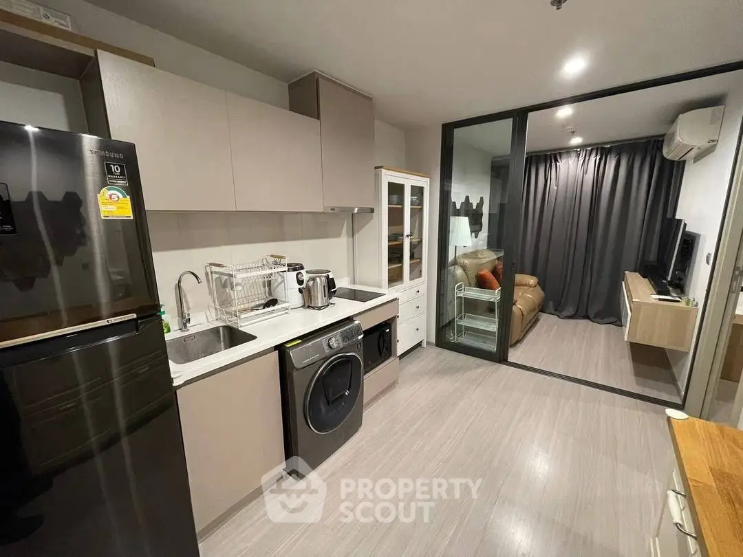 Modern kitchen with sleek appliances and adjacent cozy living room in stylish apartment.
