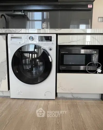 Modern kitchen with built-in washing machine and microwave, sleek cabinetry, and elegant flooring.
