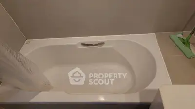 Modern bathroom with sleek bathtub and neutral tiles, perfect for relaxation.