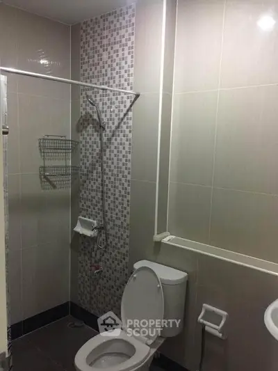 Modern bathroom with tiled walls and shower area in a real estate property.
