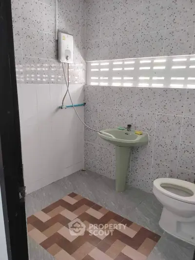 Modern bathroom with tiled walls, sink, and toilet, featuring a water heater.