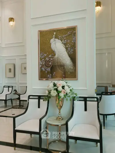 Elegant lobby with luxurious decor and peacock artwork, featuring plush seating and floral arrangement.