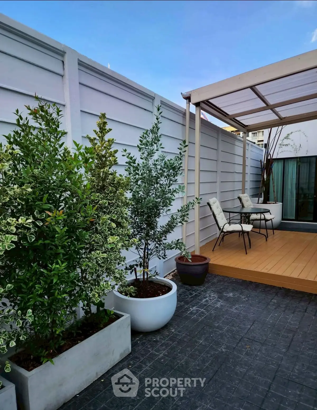 Charming rooftop terrace with modern decking and lush potted plants, perfect for relaxation and outdoor dining.