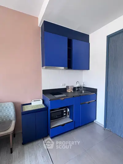 Modern compact kitchen with blue cabinets and sleek design in a stylish apartment.
