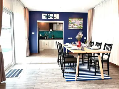 Modern dining area with stylish kitchen in open layout, featuring blue accent wall and natural light.