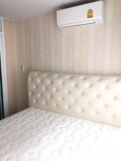Cozy bedroom with elegant tufted headboard and modern air conditioning unit.