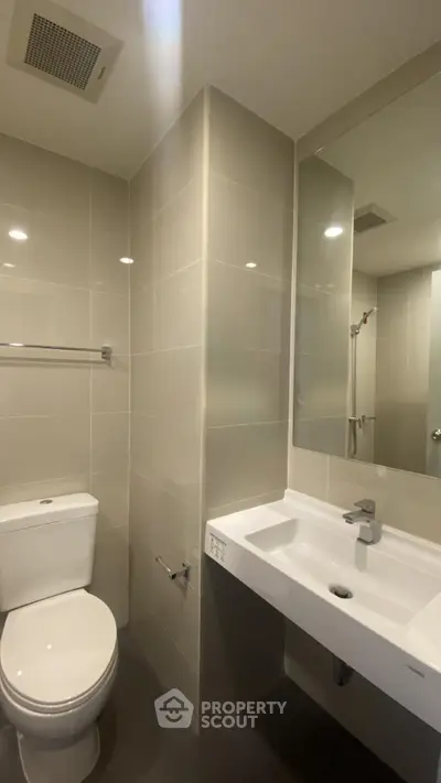 Modern bathroom with sleek fixtures and large mirror in a contemporary apartment.