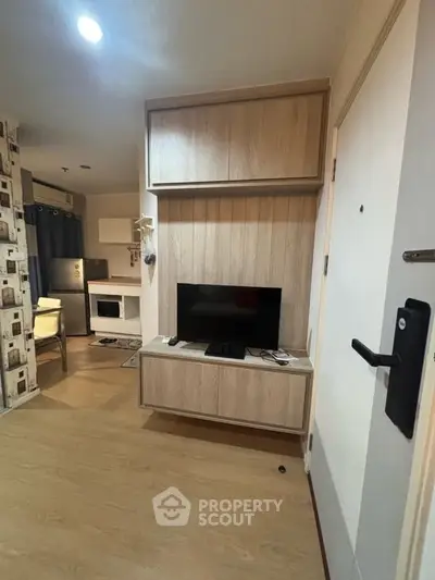 Modern living room with wooden flooring and built-in TV unit, showcasing cozy interior design.