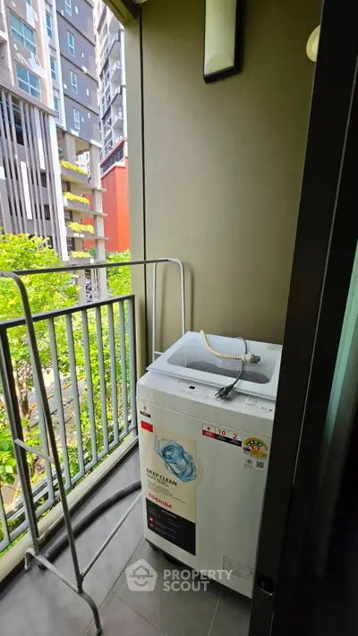 Compact balcony with washing machine and city view, ideal for urban living.