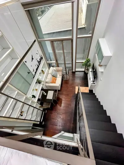 Stunning loft-style living room with high ceilings and large windows, offering abundant natural light and modern decor.