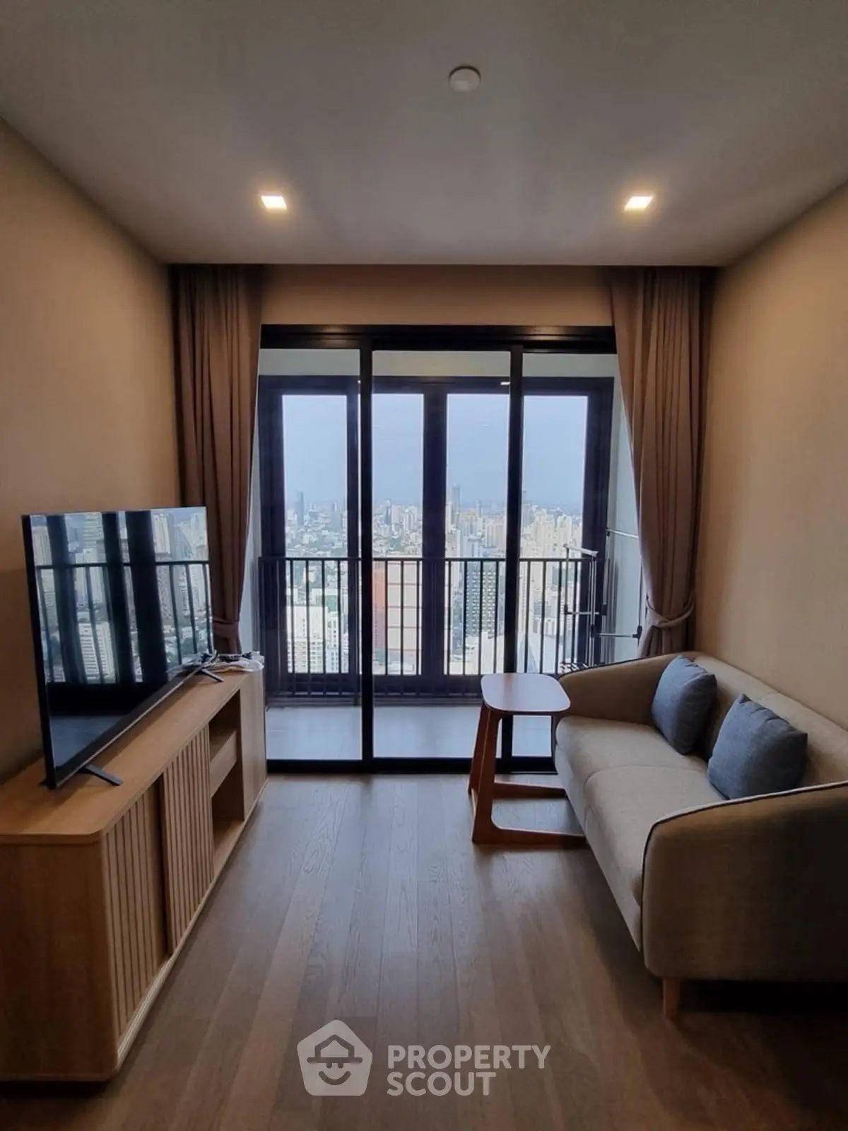 Modern living room with city view, featuring sleek furniture and large windows for natural light.