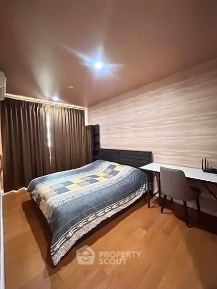 Cozy bedroom with wooden flooring, stylish bed, and study desk, perfect for relaxation and productivity.
