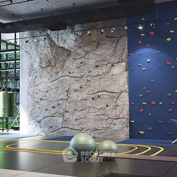 Modern gym with climbing wall and exercise equipment in luxury building.