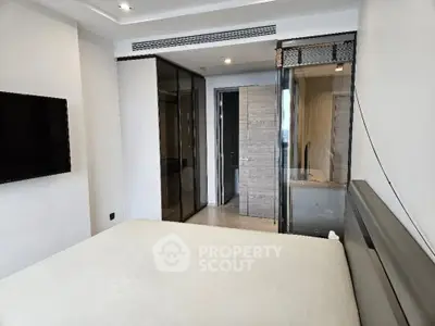 Modern bedroom with sleek design and glass partition leading to bathroom