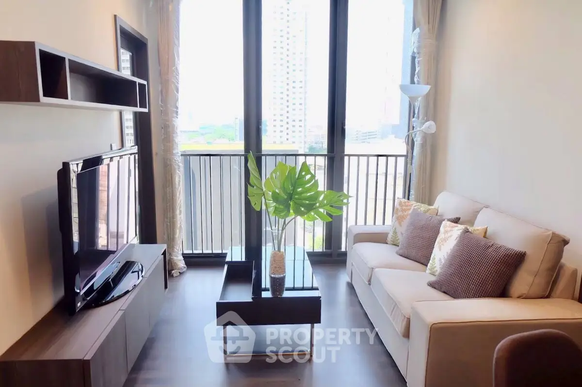 Modern living room with balcony view, stylish furniture, and natural light in urban apartment.