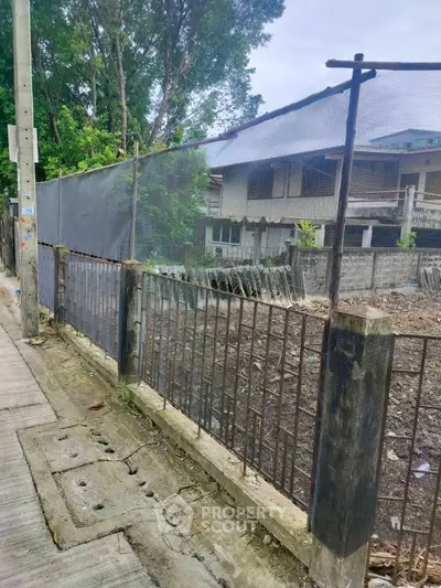 Vacant lot with metal fence and nearby residential building
