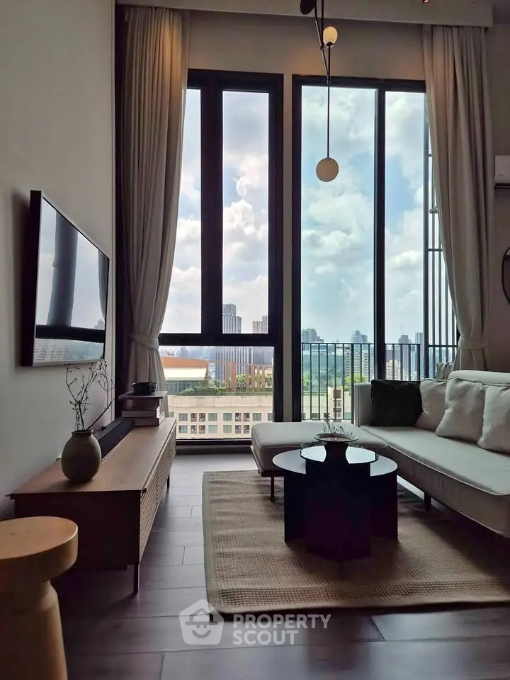 Modern living room with floor-to-ceiling windows offering stunning city views, stylish furniture, and elegant decor.