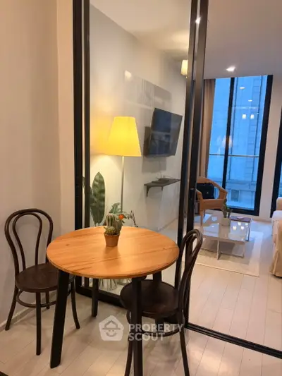 Modern living room with glass partition, cozy seating, and stylish decor in urban apartment.