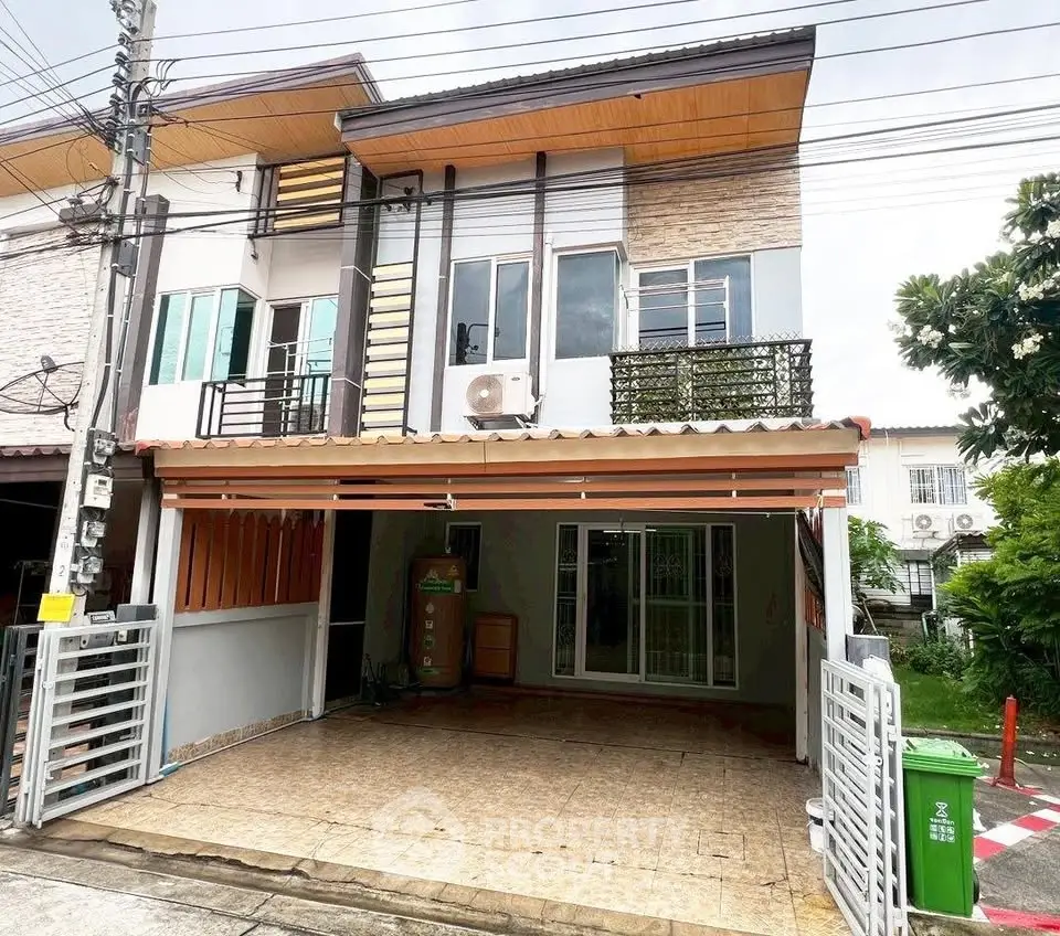 Modern two-story townhouse with covered carport and balcony in a suburban neighborhood.