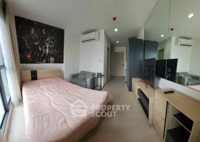 Modern bedroom with stylish decor, featuring a cozy bed, sleek furniture, and a large mirror for spacious feel.