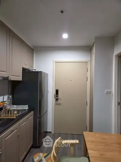 Modern kitchen with sleek cabinetry and stainless steel fridge in cozy apartment.