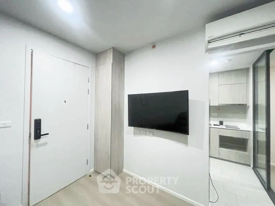 Modern apartment interior with sleek kitchen and wall-mounted TV, showcasing minimalist design and efficient use of space.