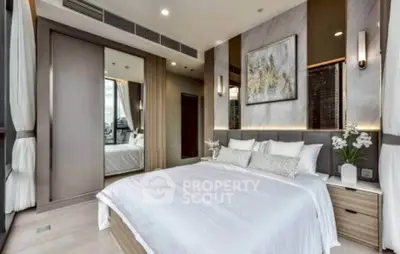 Luxurious modern bedroom with elegant decor and large mirror reflecting natural light.