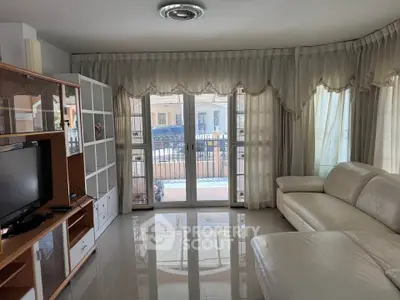Spacious living room with elegant curtains and modern furniture, featuring a large balcony view.