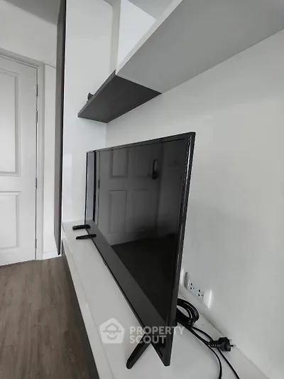 Modern living room with sleek TV and stylish shelving in a contemporary apartment.