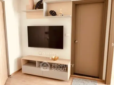 Modern living room with wall-mounted TV and stylish shelving in a cozy apartment.