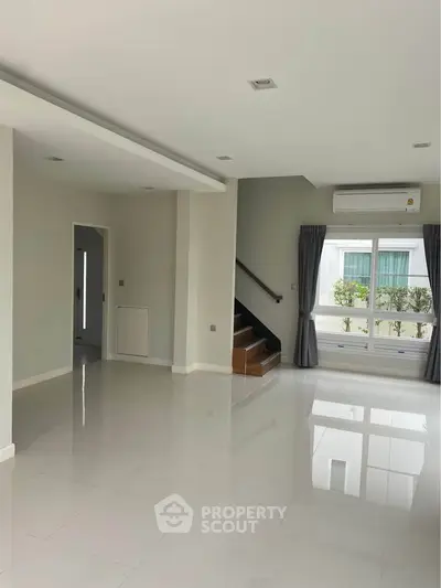 Spacious modern living room with glossy floors and large windows offering natural light.