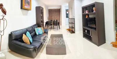 Spacious living room with modern black leather sofa and entertainment center