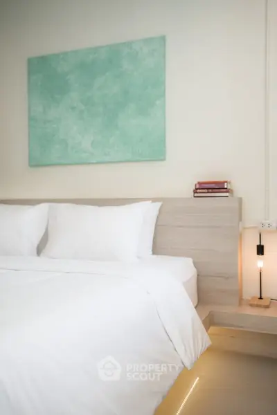 Modern bedroom with minimalist decor and soft lighting, featuring a stylish headboard and abstract wall art.