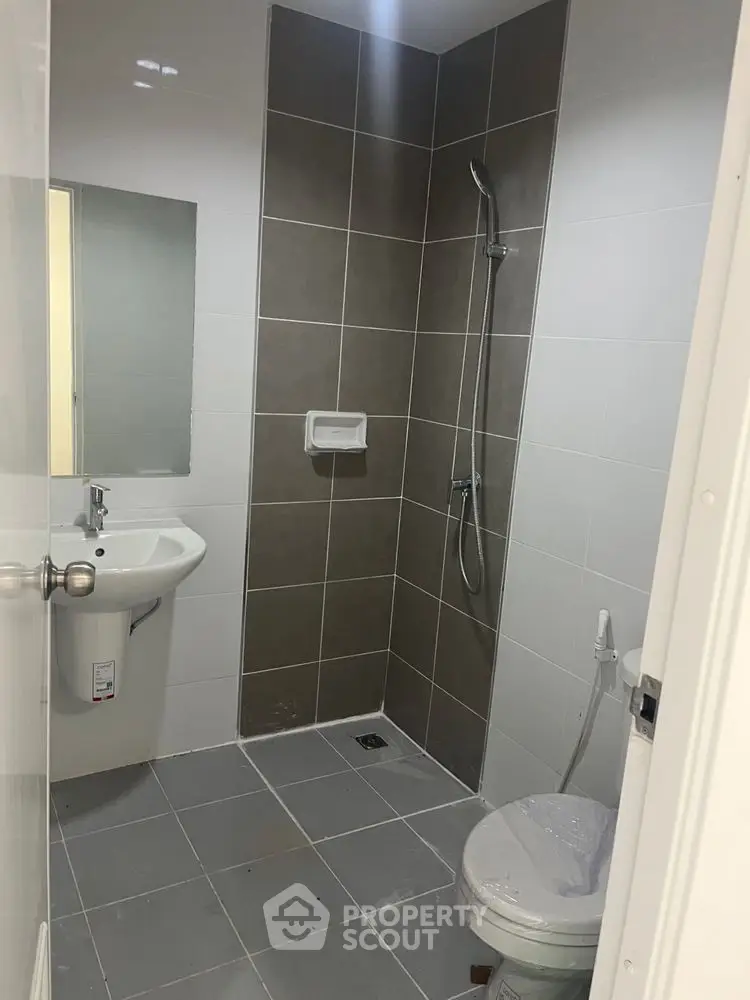Modern bathroom with sleek tiles and shower area in contemporary apartment.
