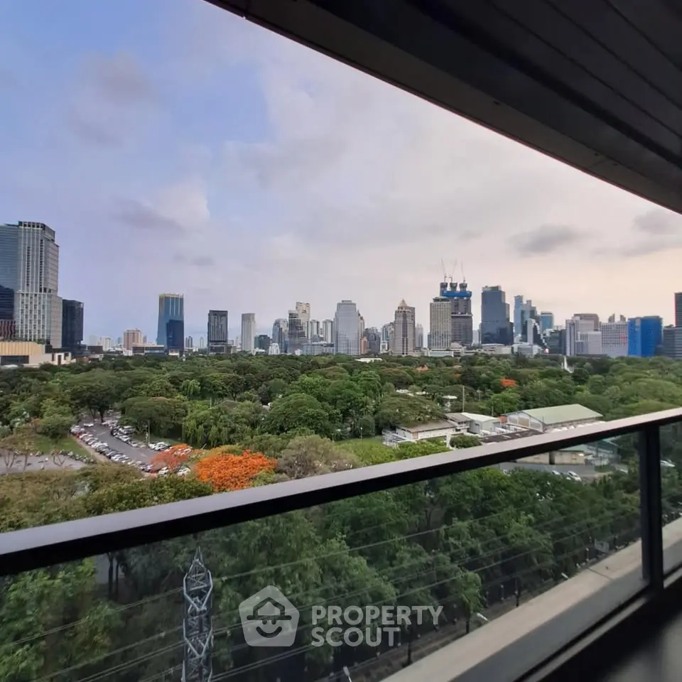 Stunning cityscape view from a high-rise balcony overlooking lush greenery and skyline.