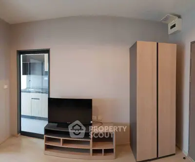 Modern apartment interior with TV, wardrobe, and view into kitchen