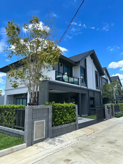 Modern two-story house with sleek design and lush greenery in a serene neighborhood.